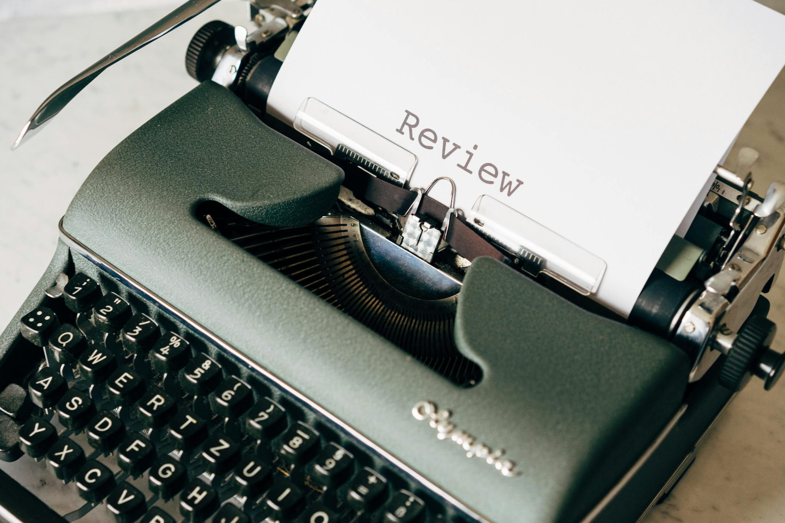 Home Classic green typewriter with paper displaying 'Review', perfect for creative writing themes.